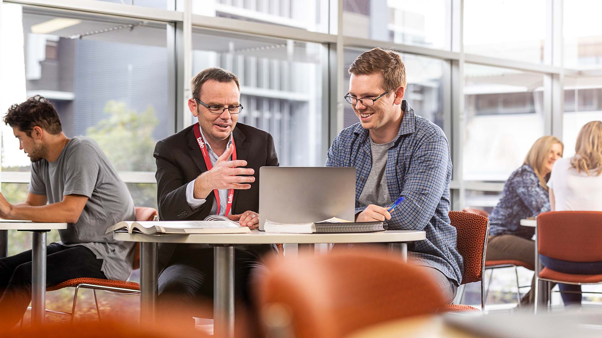 Photograph of people discussing information on a laptop